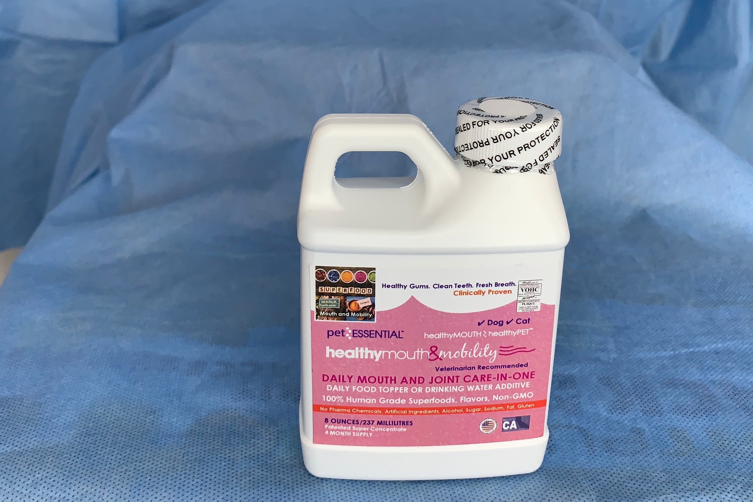 Bottle of Pet Essential Healthy Mouth & Joint supplement on a blue background